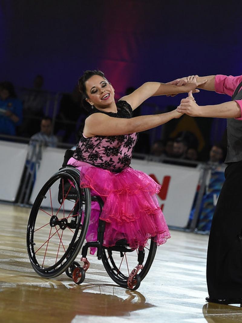 Female dancer in wheelchair and standing male partner dance to quickstep