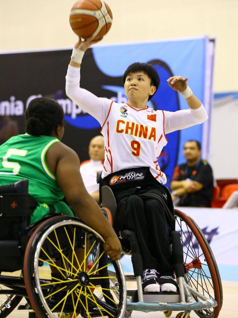 Chinese woman in wheelchair about to shoot basketball