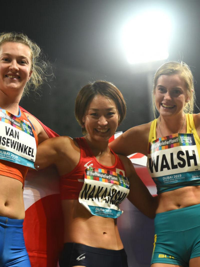Three female longer jumpers pose for a photo with their respective flags