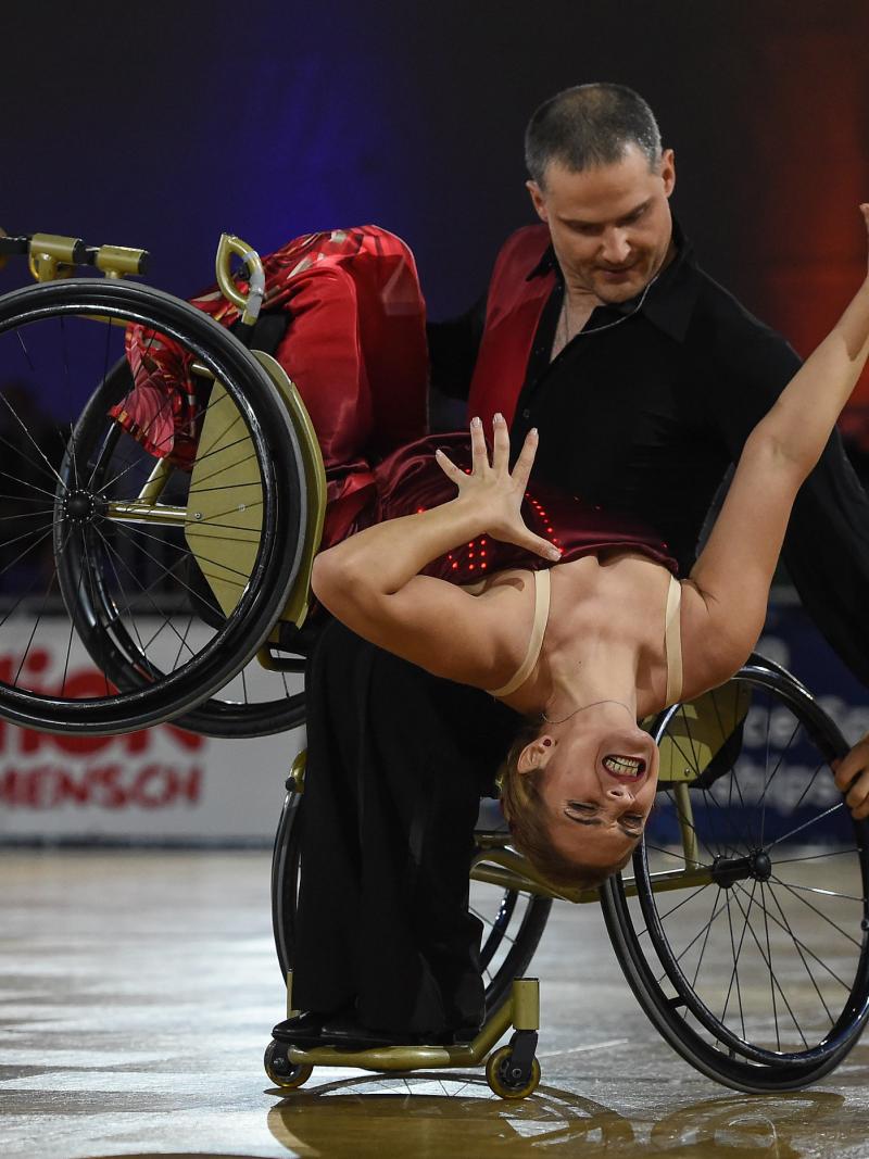 Man in wheelchair dips female wheelchair dance partner