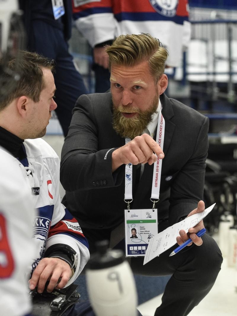 A man in suit talking to a Para ice hockey player on the ice