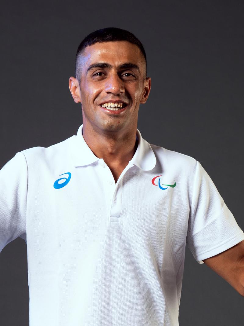 A man smiling to camera wearing a white shirt with the Agitos