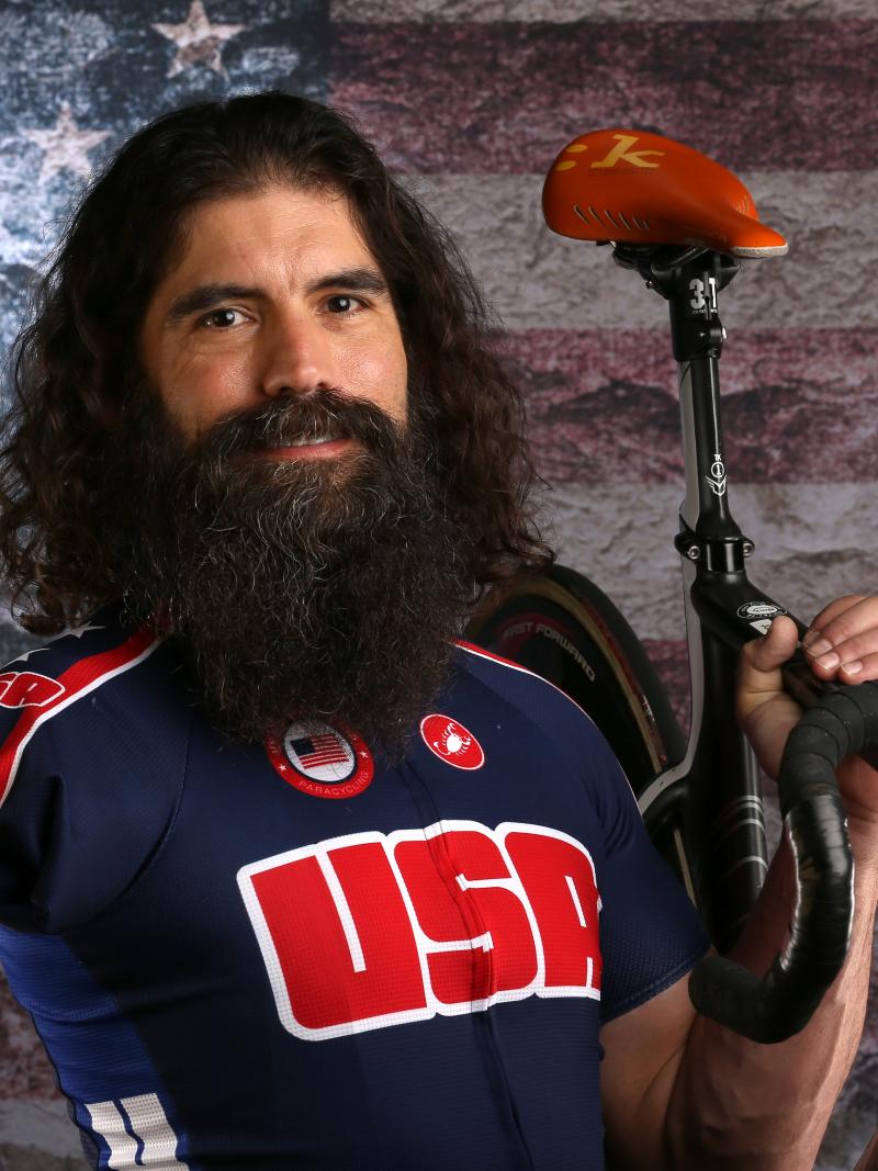 Portrait of man with big beard and missing right arm holdings his bike 