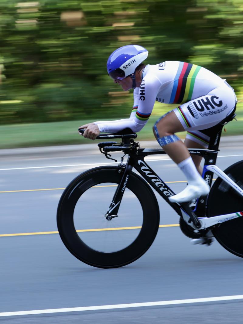 Female cyclist rides on the road with a rainbow jersey