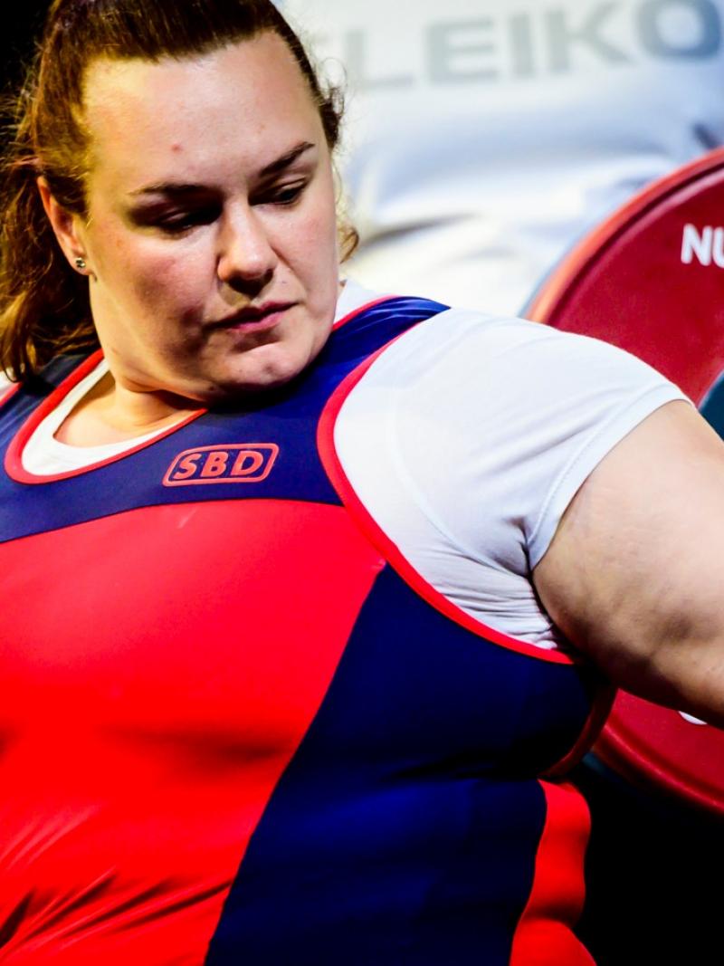 A woman with her hand on a powerlifting bar