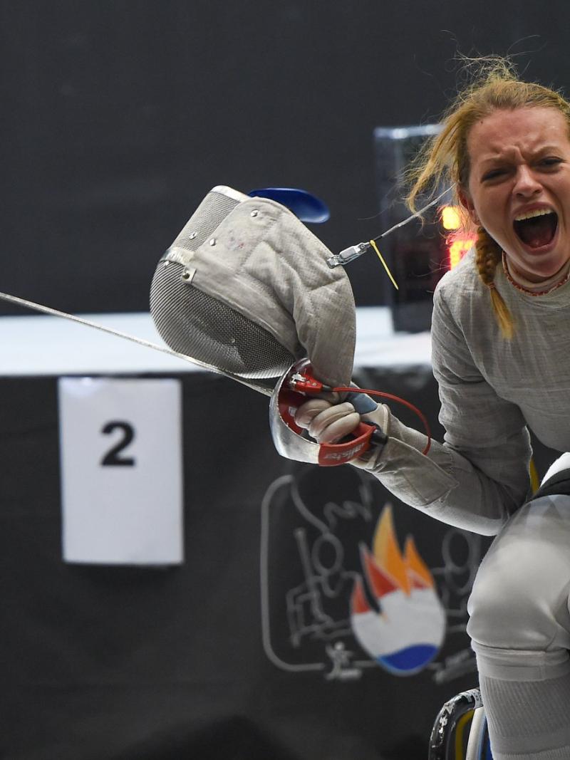 Female wheelchair fencer removes mask to celebrate