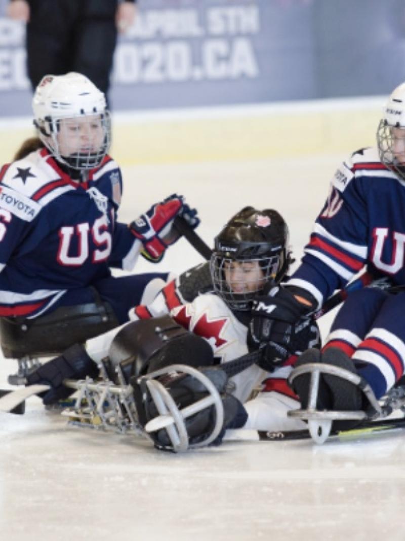 US and Canadian female Para ice hockey players fight for the puck
