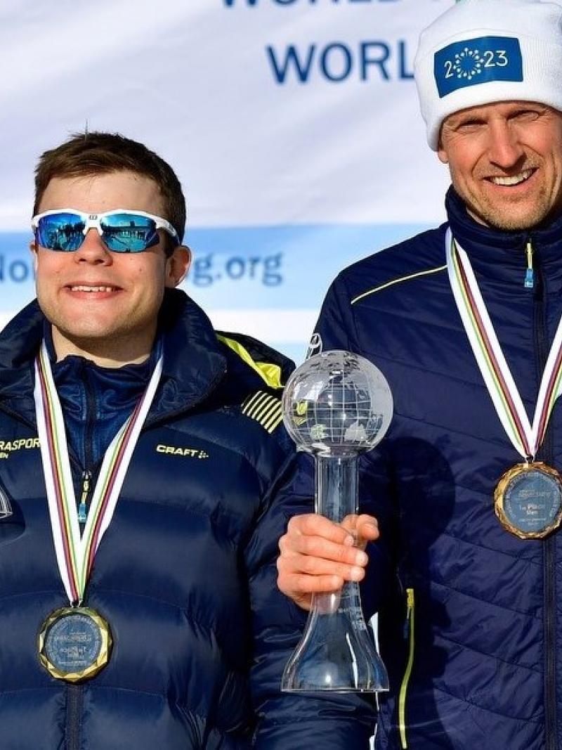 Two men holding with a medal showing their Crystal Globe trophy