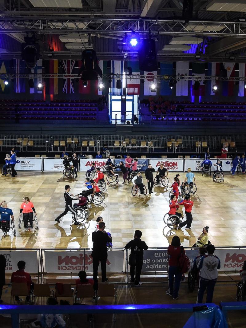 A group of dancers in wheelchairs on a court with their dancing partners