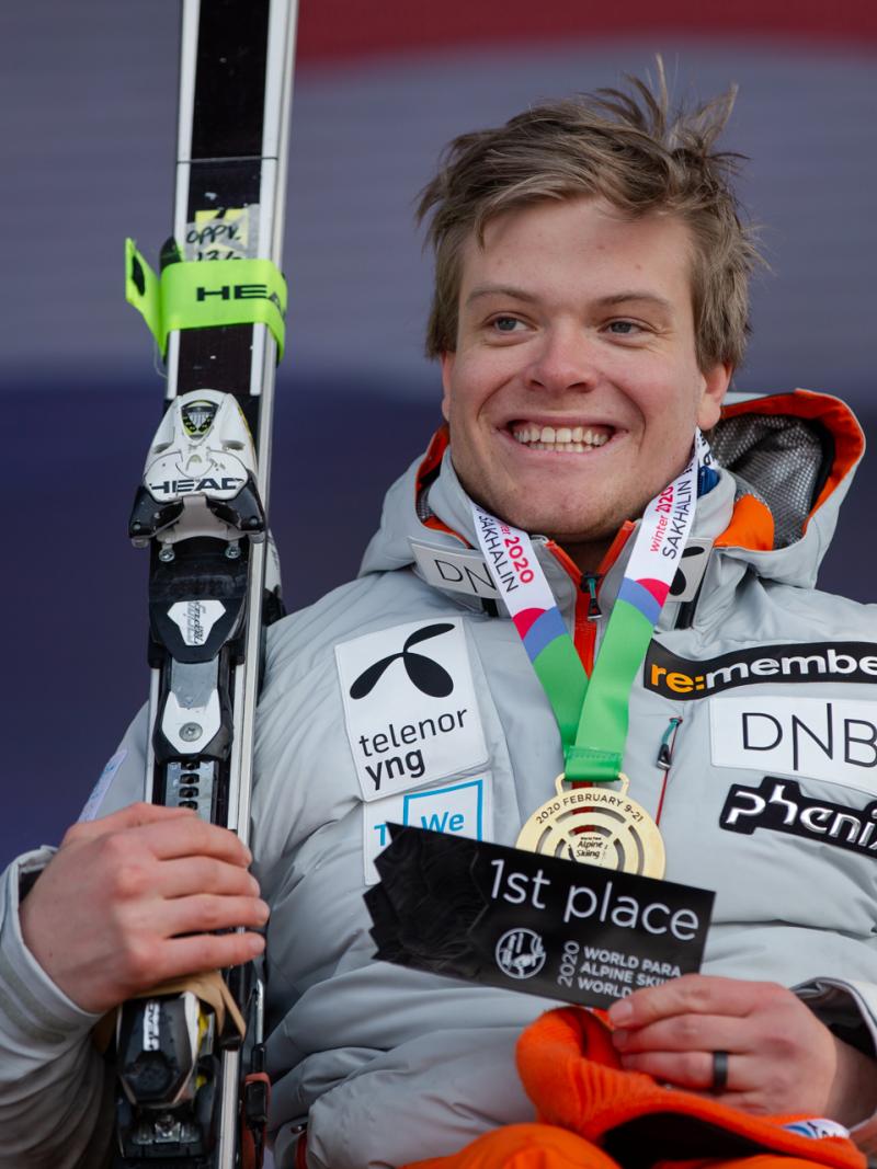 A man with a gold medal smiling and holding a skiing
