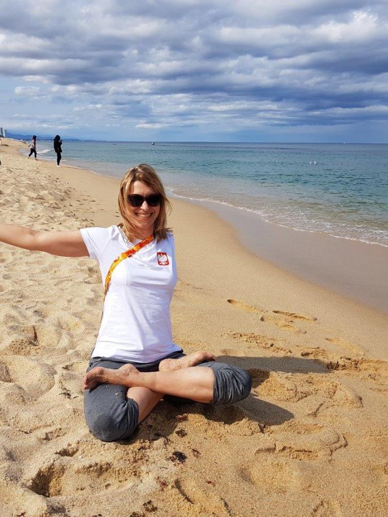 Woman with left arm amputation sits on sandy beach