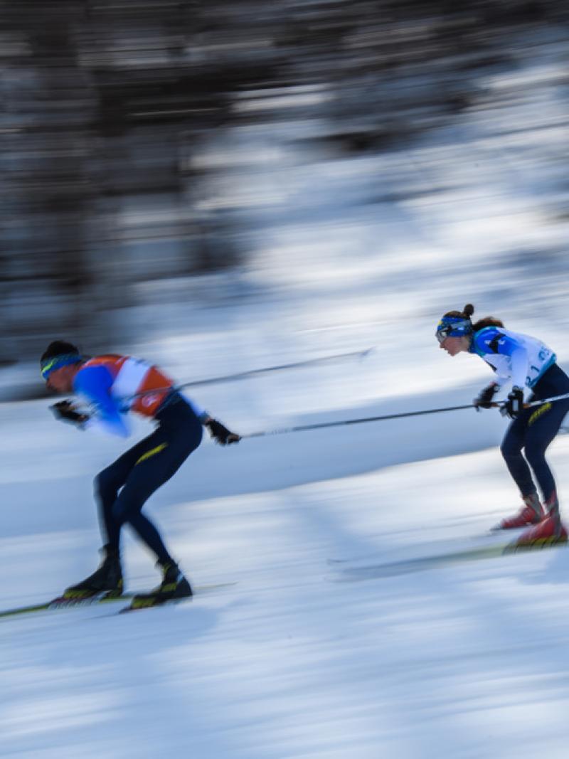 A male guide and a female athlete competing in Para biathlon