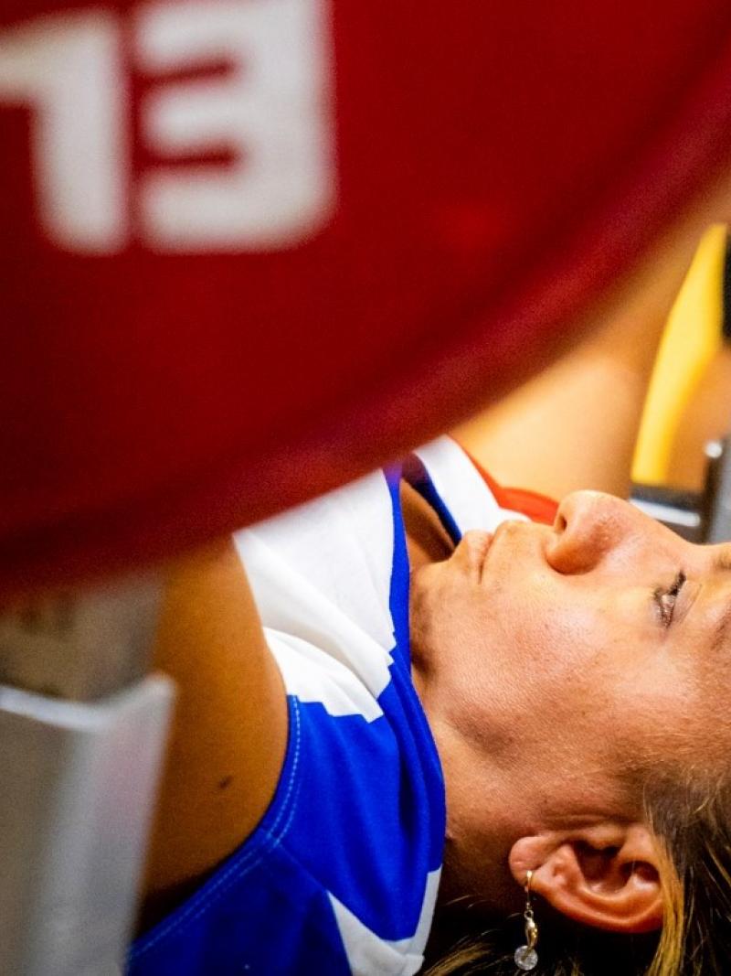 A female powerlifter on a bench preparing to lift the bar
