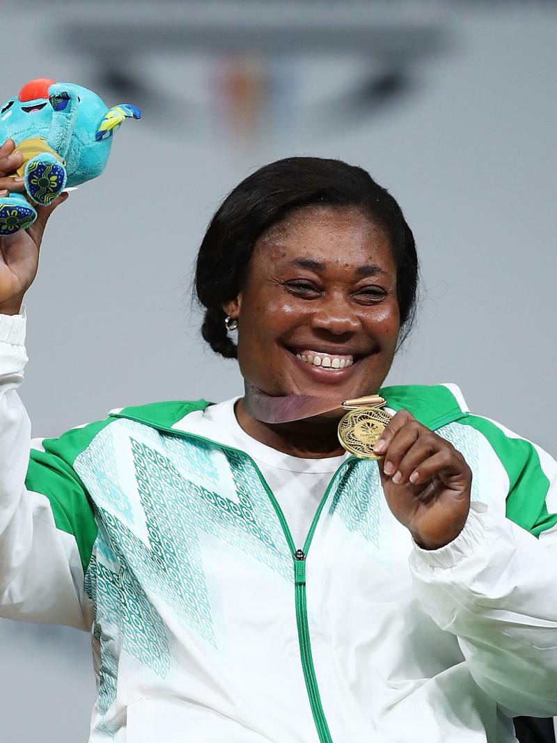 A woman holding a mascot with the right hand and showing the medal with her left hand