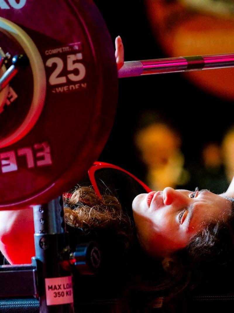 A woman on a bench press preparing to lift the bar