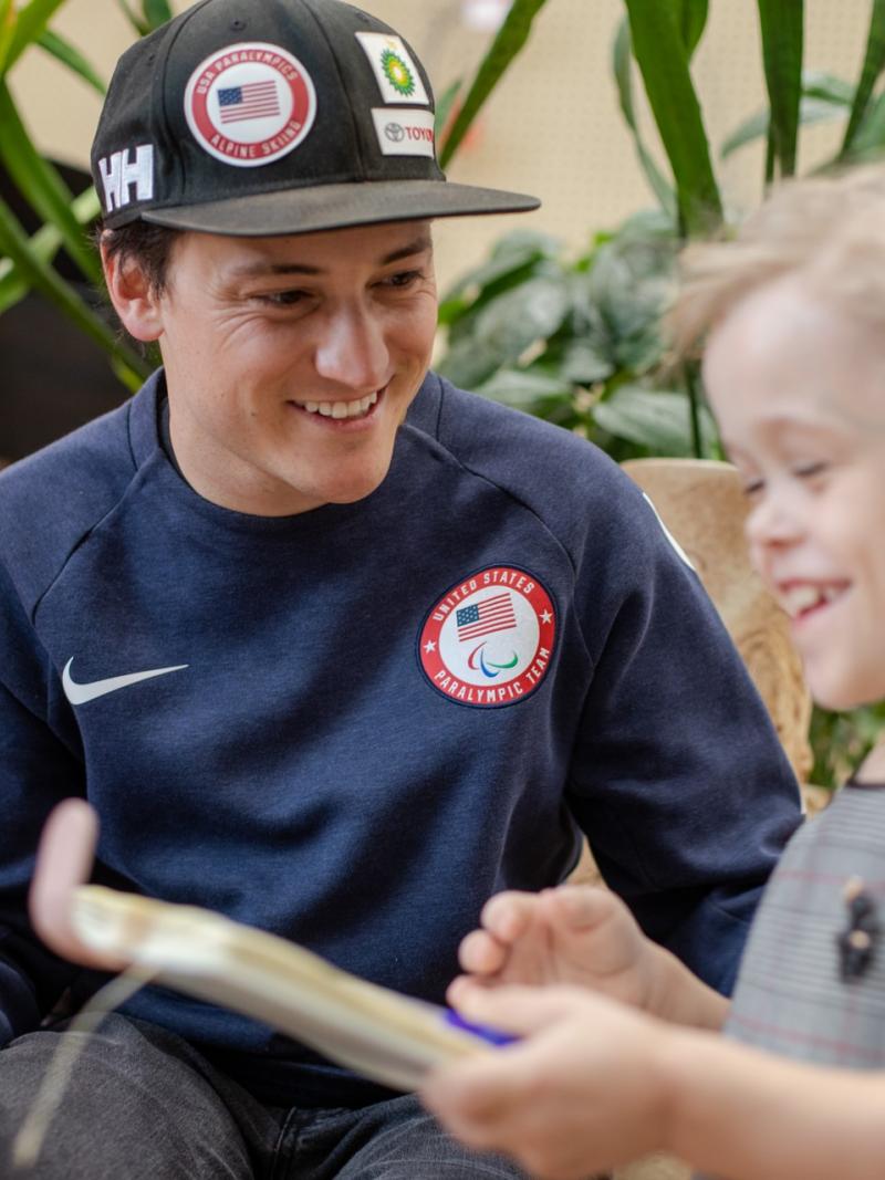 A man wearing a black cap talking to a little girl