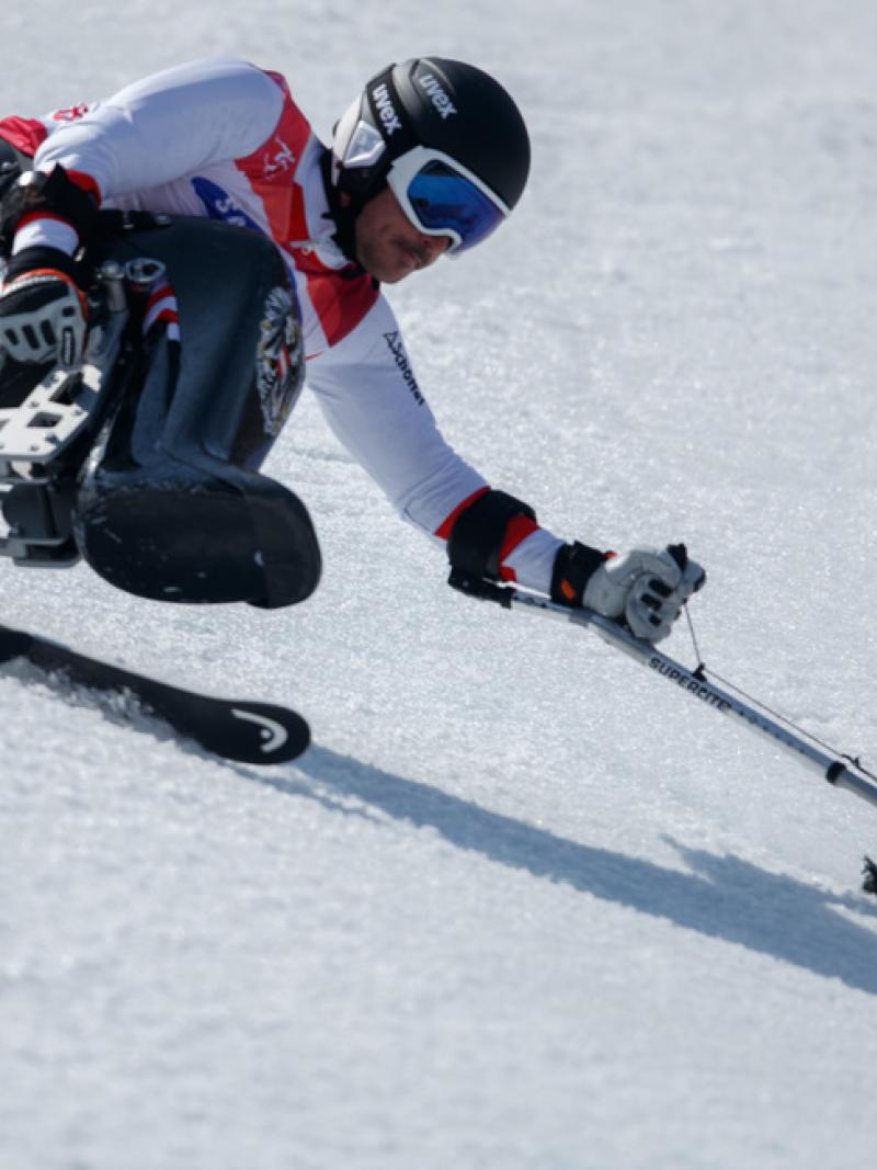 A male sit-skier making a turn in the snow