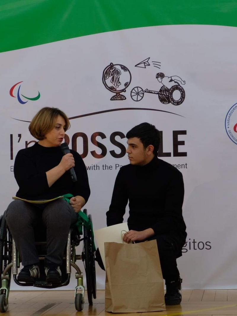 Woman in wheelchair speaks with student winner