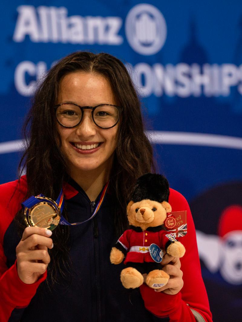 A woman wearing glasses showing her gold medal 