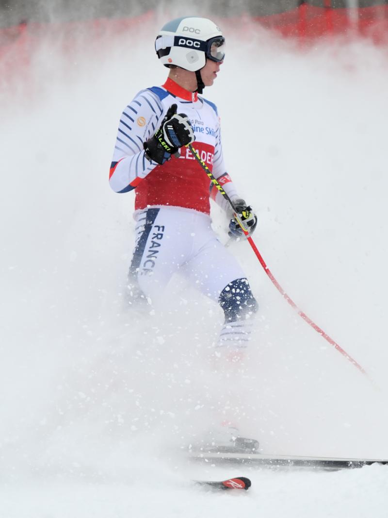 A male skier with a wave of snow behind him