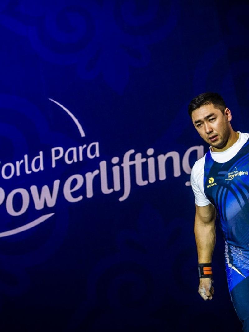 An athlete walking in front of a banner written World Para Powerlifting