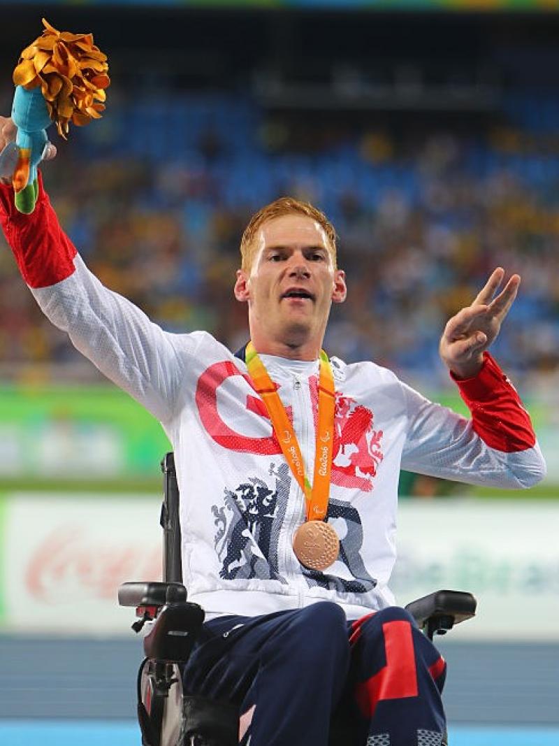 Male British athlete with cerebral palsy celebrates on the podium