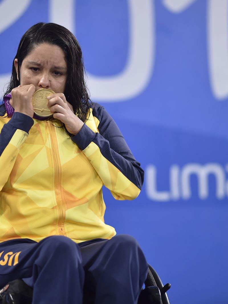 A woman in a wheelchair kissing a gold medal