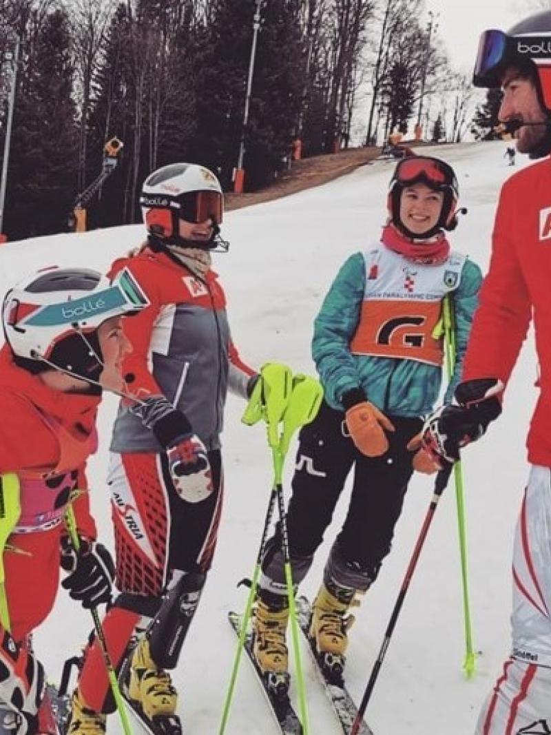 A group of three female and one male skier talking on a ski slope