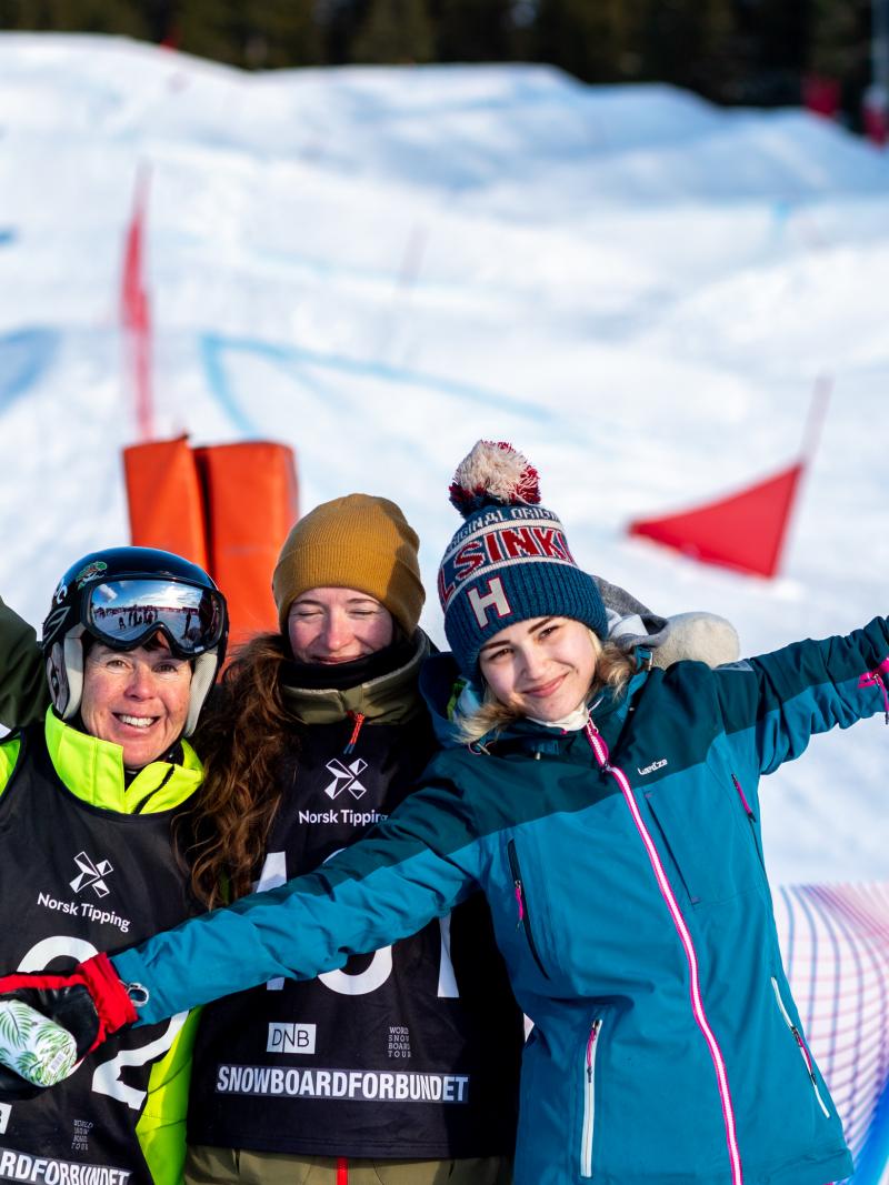 Three female Para snowboarders hugging and posing for a picture