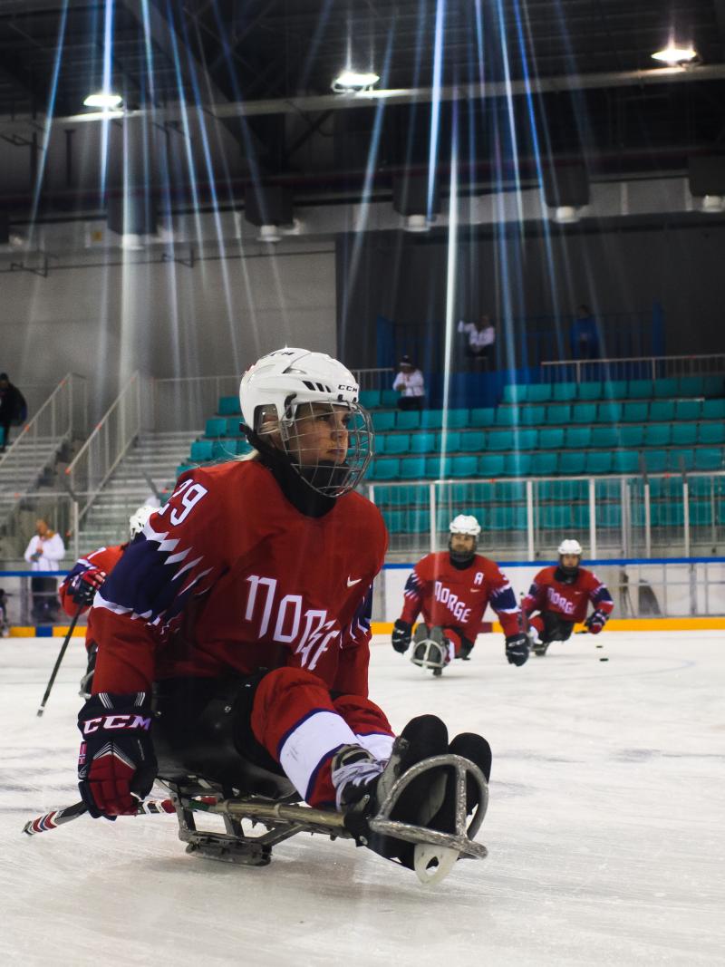 A female Para ice hockey player practising with her teammates on a rink