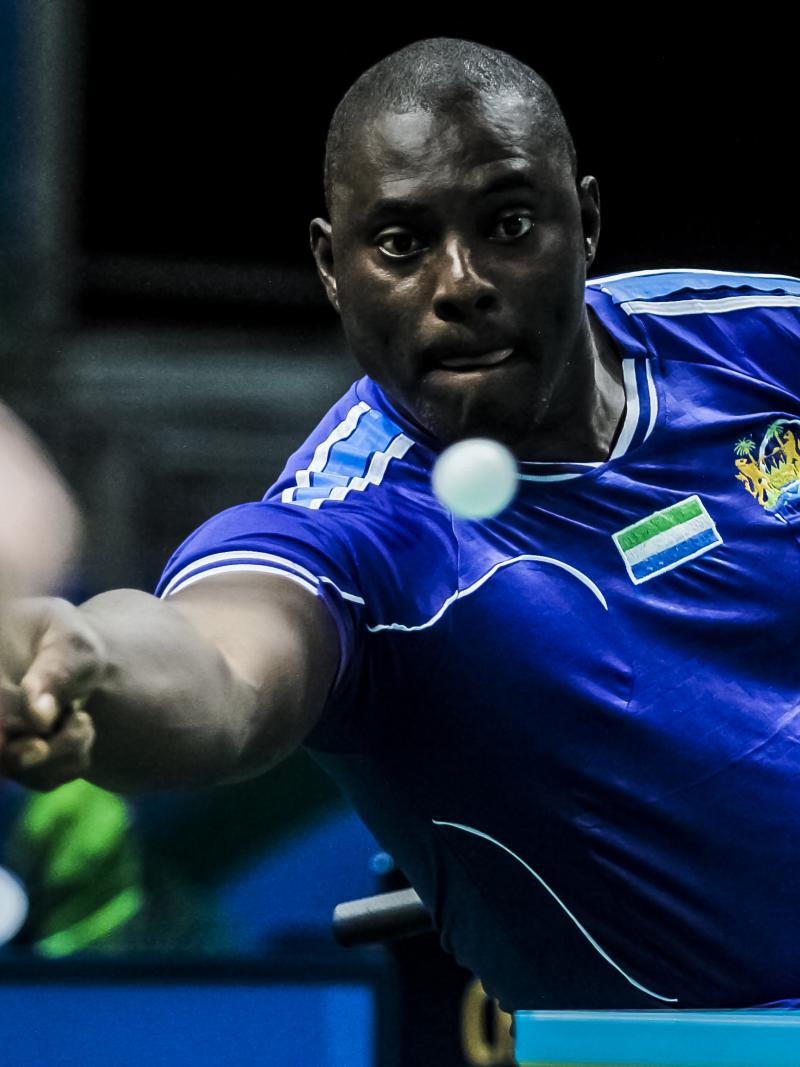 African table tennis player reaches for a shot