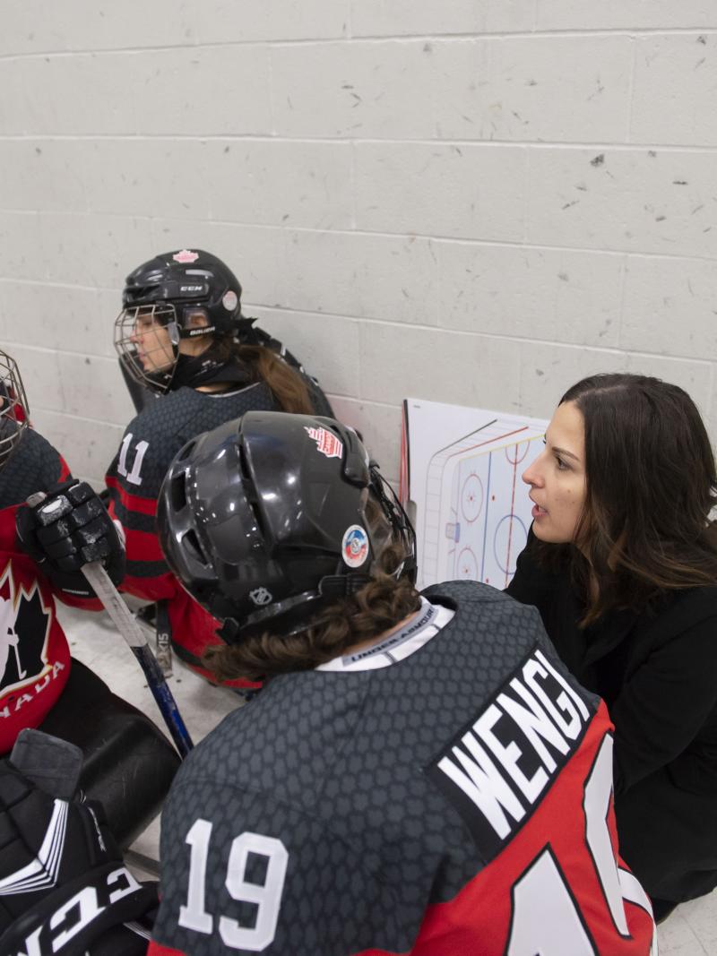 A woman talking to two women in hockey sledges