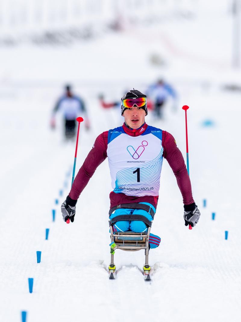 A man in a sit-ski competing in a  Para cross-country race
