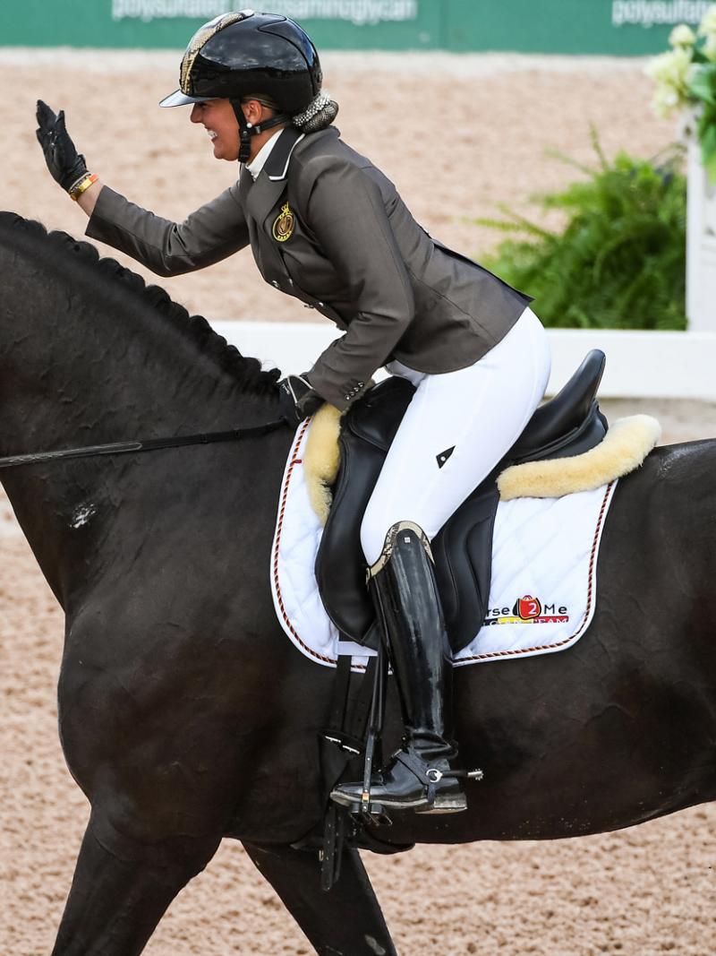 Woman riding horse and patting it on the head
