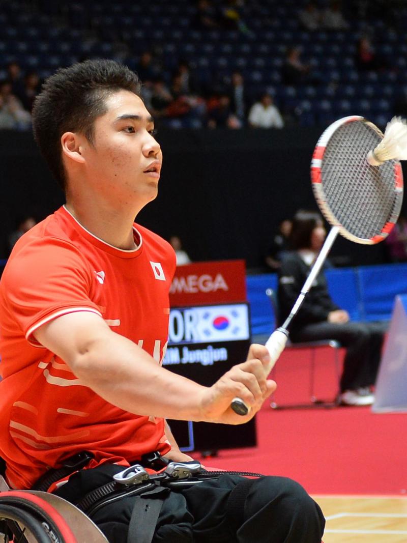 Japanese male badminton player in wheelchair hits a return