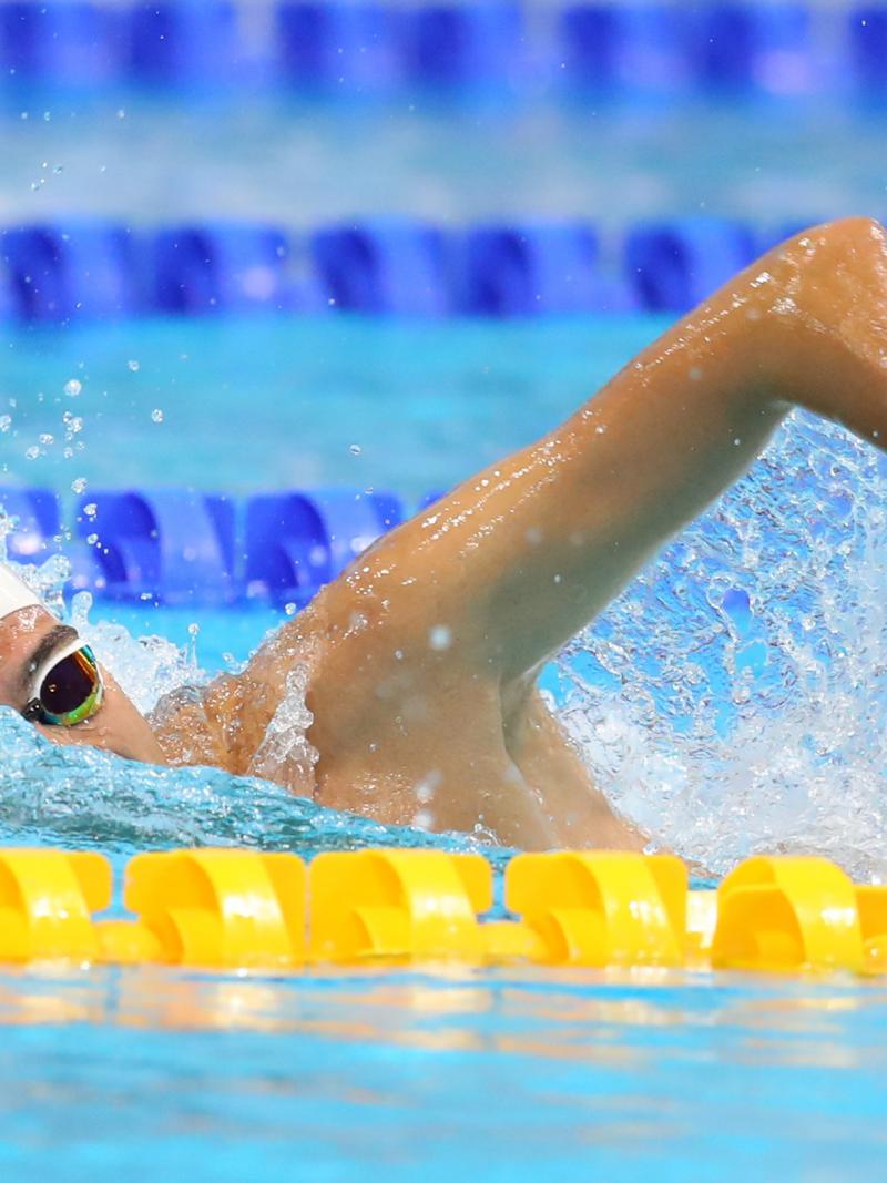 A male swimmer without his left hand swimming a pool