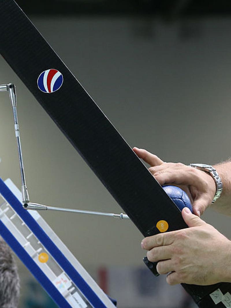 El atleta masculino de Boccia usa un puntero para golpear la pelota con su asistente ajustando la rampa
