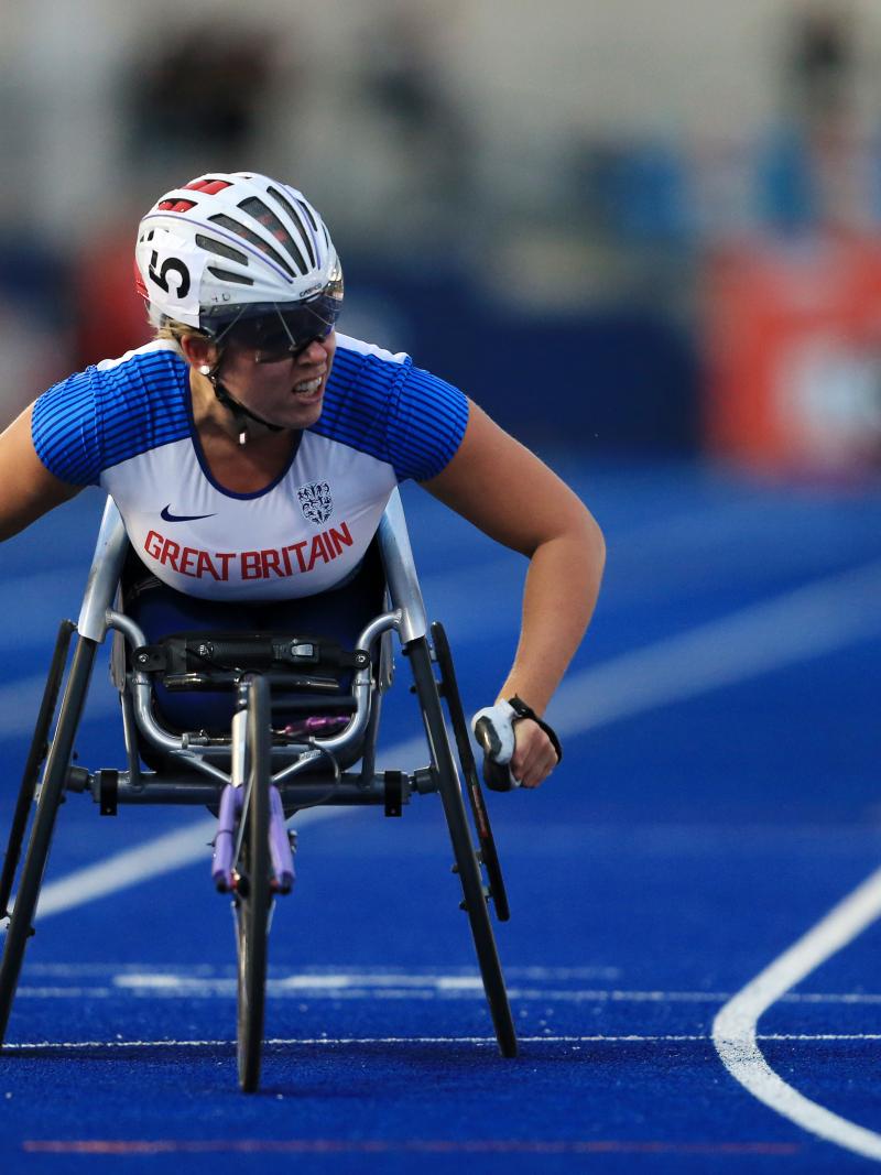 A female wheelchair racer crossing the line on a blue track