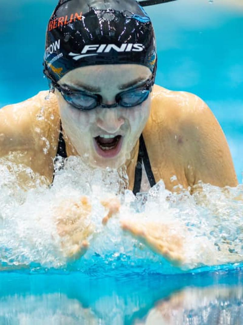 A woman with a black cap swimming breaststroke