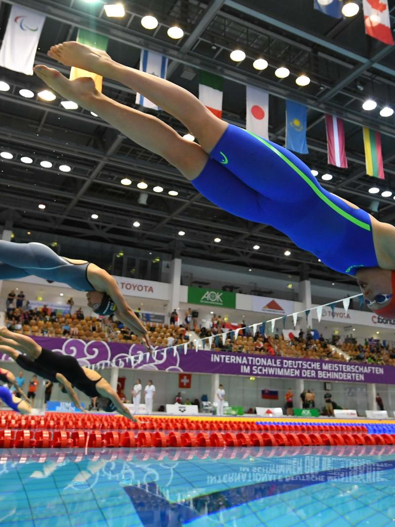 A group of seven female swimmers jumping in the water 