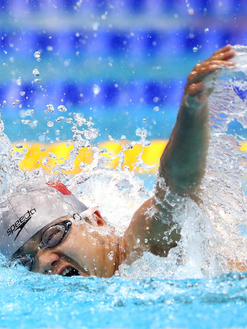 A man with a grey cap swimming in a pool