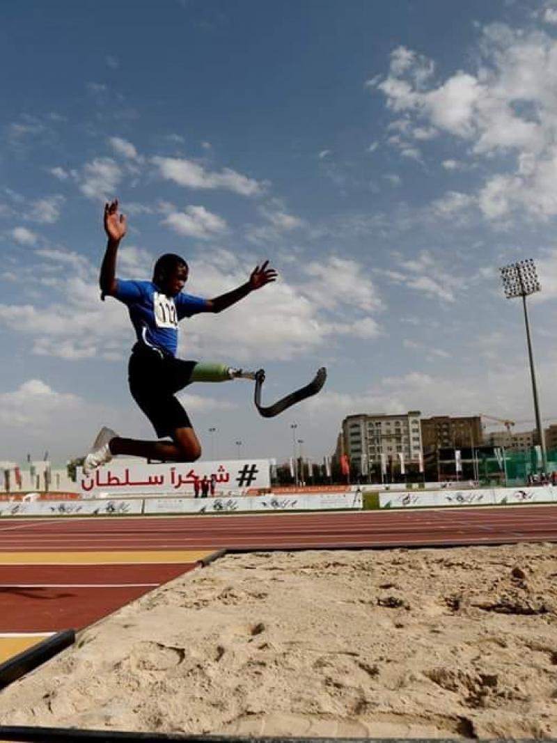 A man with a prosthetic leg jumping in an athletics track
