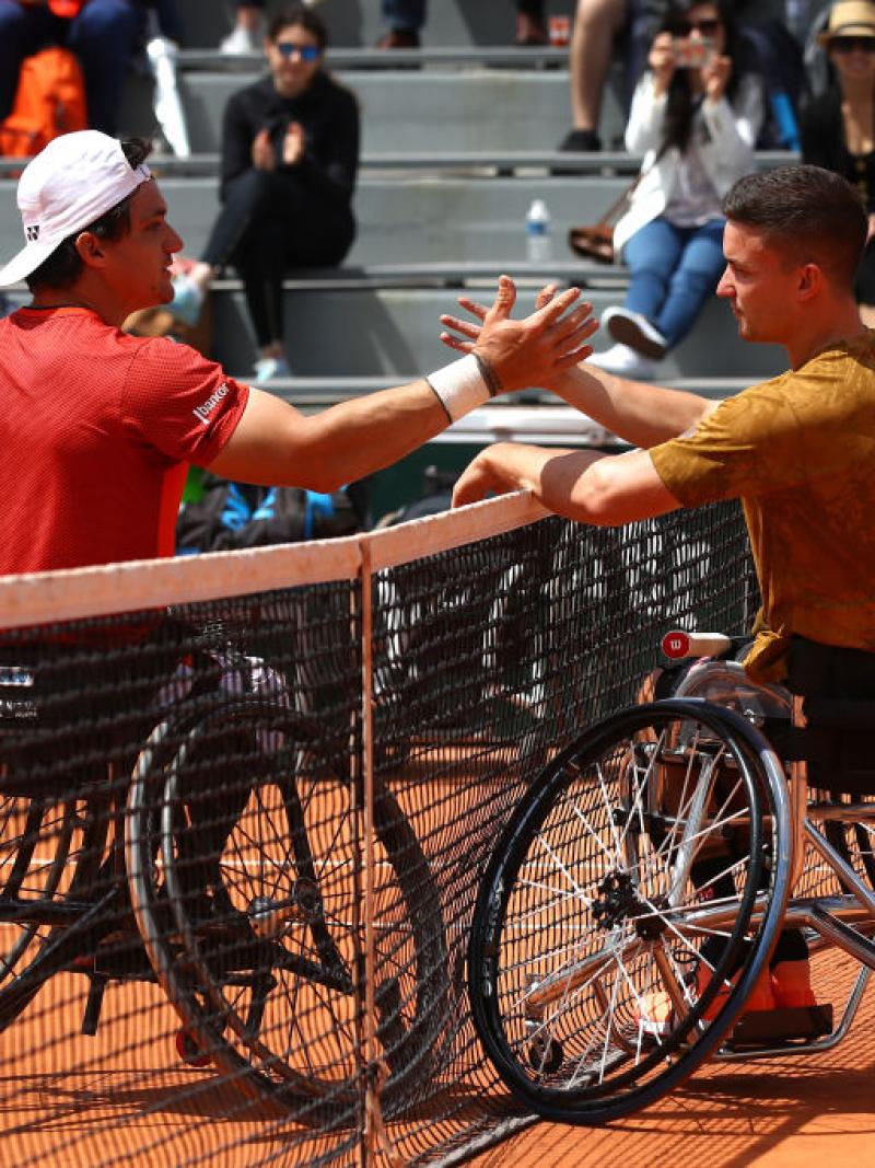 Two male wheelchair tennis players shake hands after a match