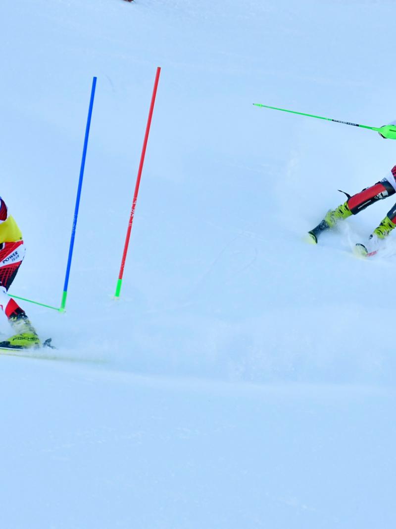 A female Para alpine skier following her guide in a competition in the snow