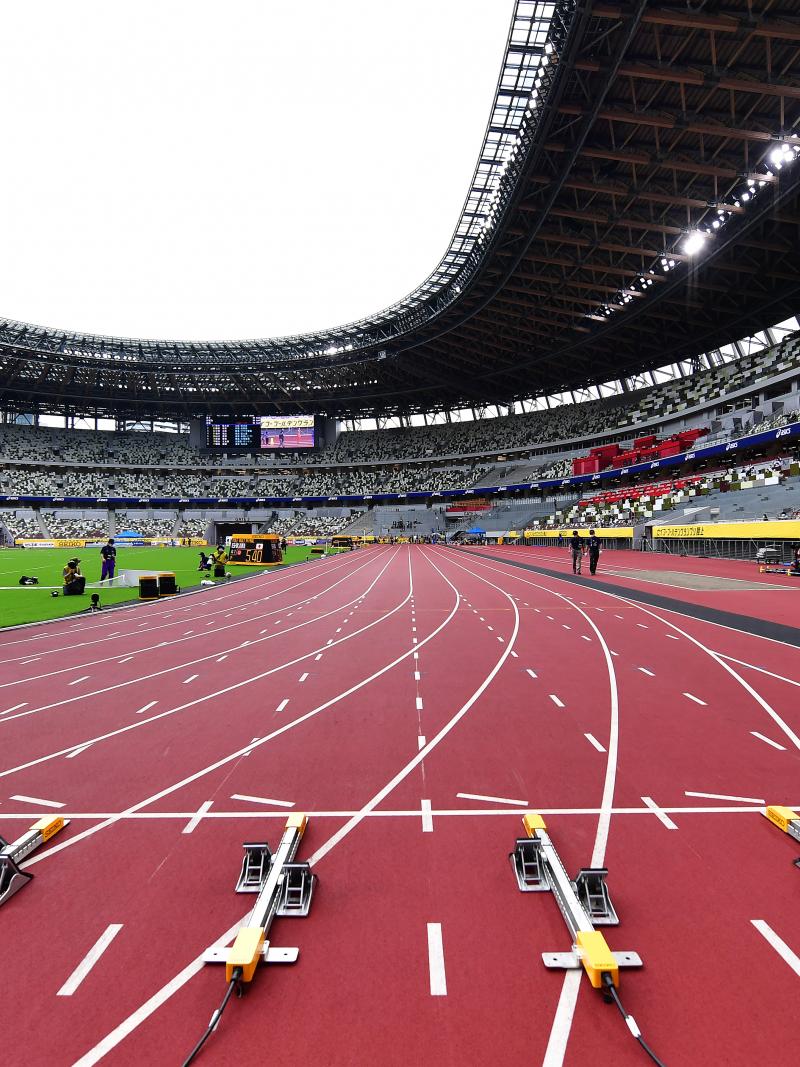 The view of a stadium with a red athletics track seen by the starting line