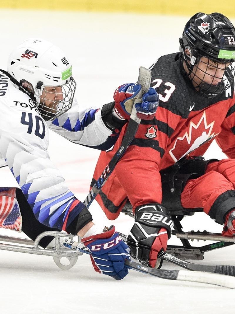 Two men competing in sledges on a Para ice hockey game