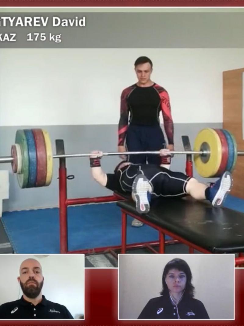 A screen showing a man lifting weight in a Para powerlifting competition and four windows showing four different persons watching it