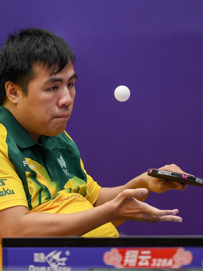 Man in wheelchair serves a table tennis ball