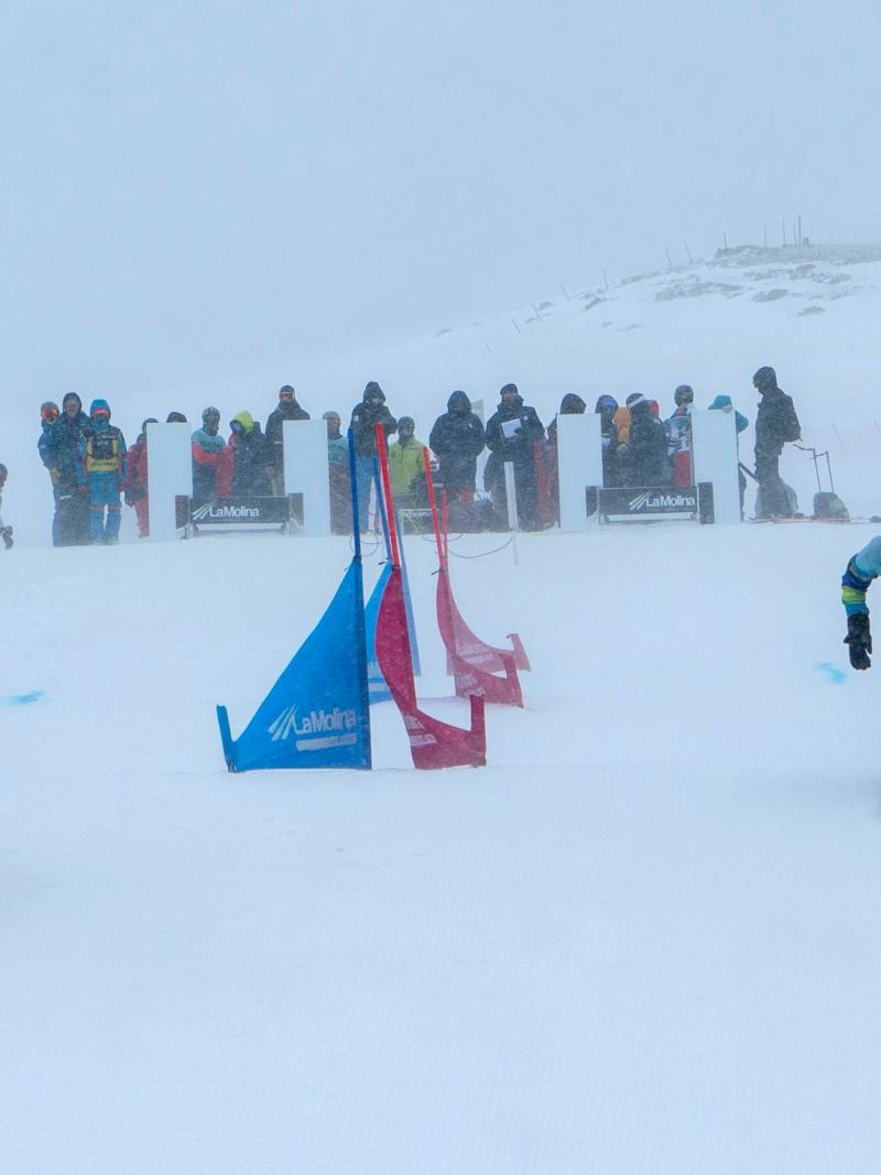 Two male Para snowboarders competing with a group of people watching in the background
