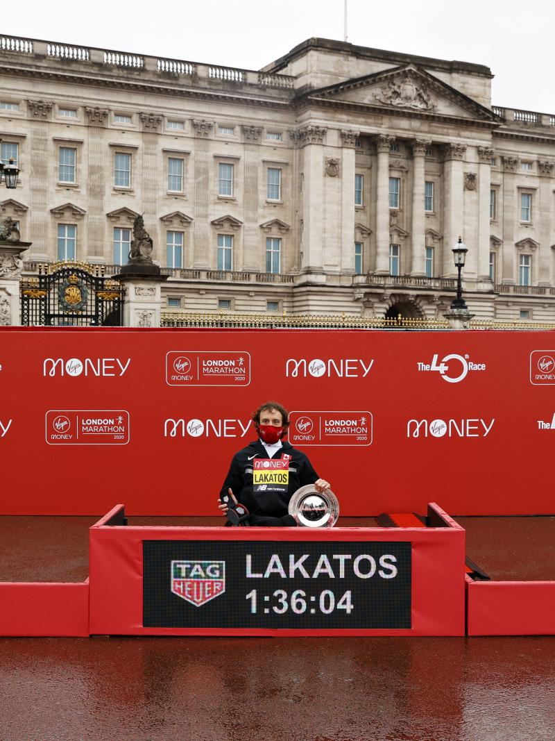 Three men in wheelchairs and face masks in a podium in front of Buckingham Palace in London
